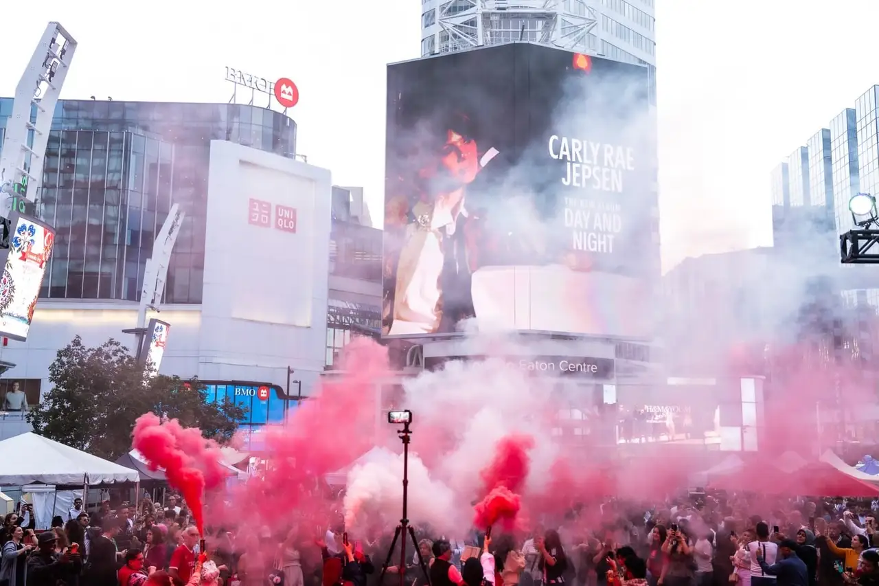 Red flares light up the crowd at dusk below the big screens of Sankofa Square.