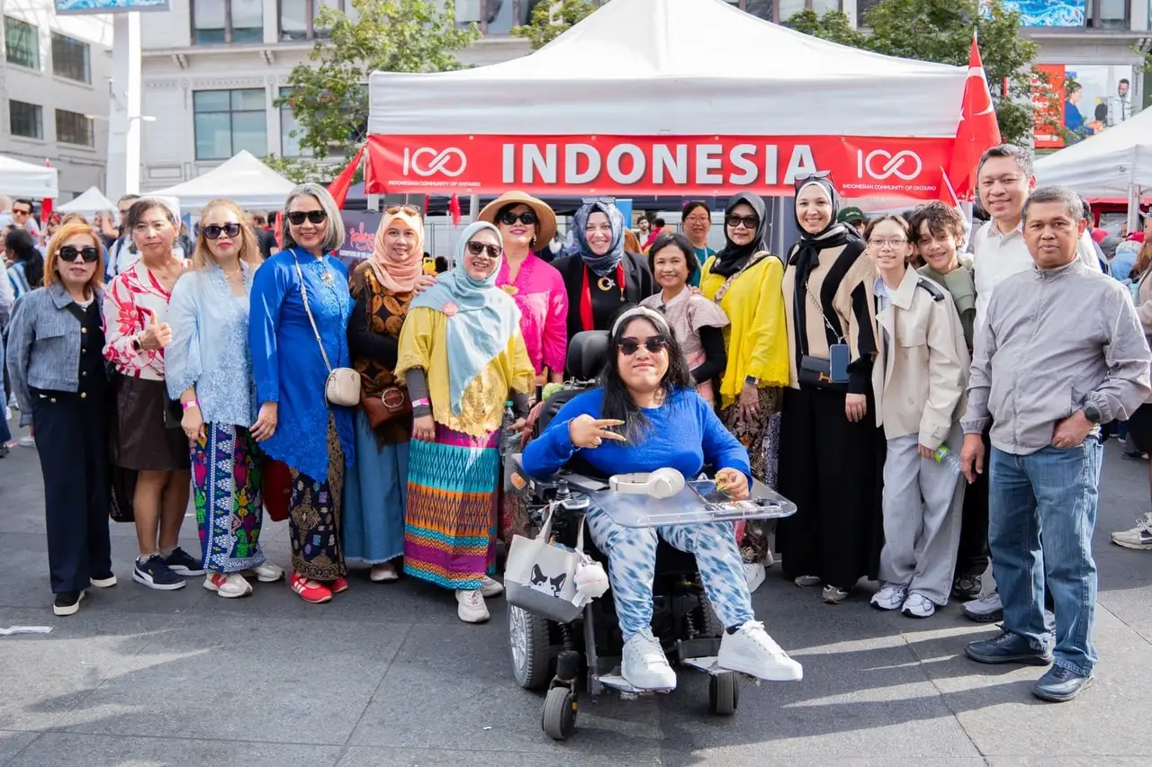 Visitors, several in traditional dress, gather in front of the Indonesia tent.
