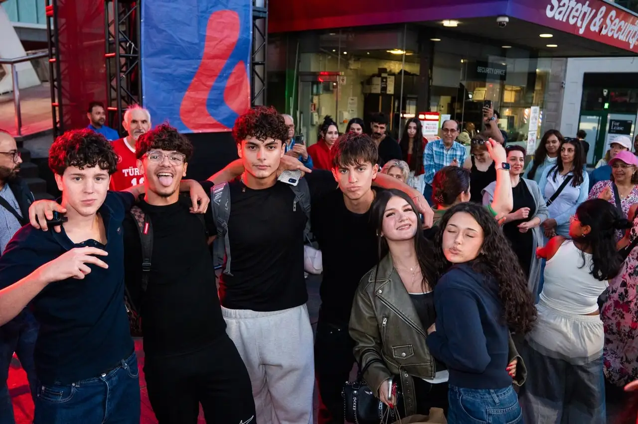 A group of teenagers pose together in the evening crowd.