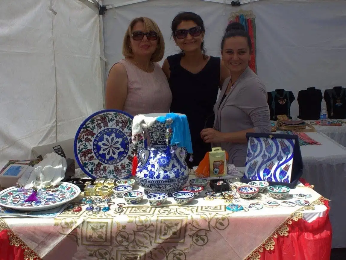 Three women behind a table of hand-painted blue and white ceramics.