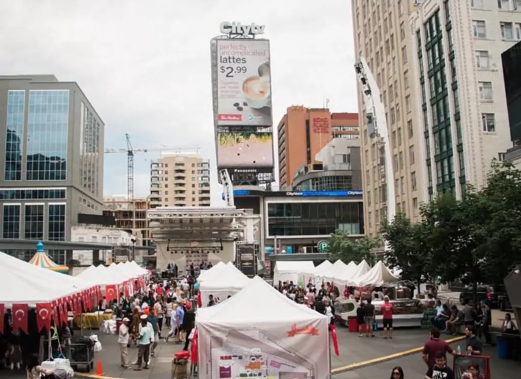 White market tents with red trim line the square below the Dundas Street towers.